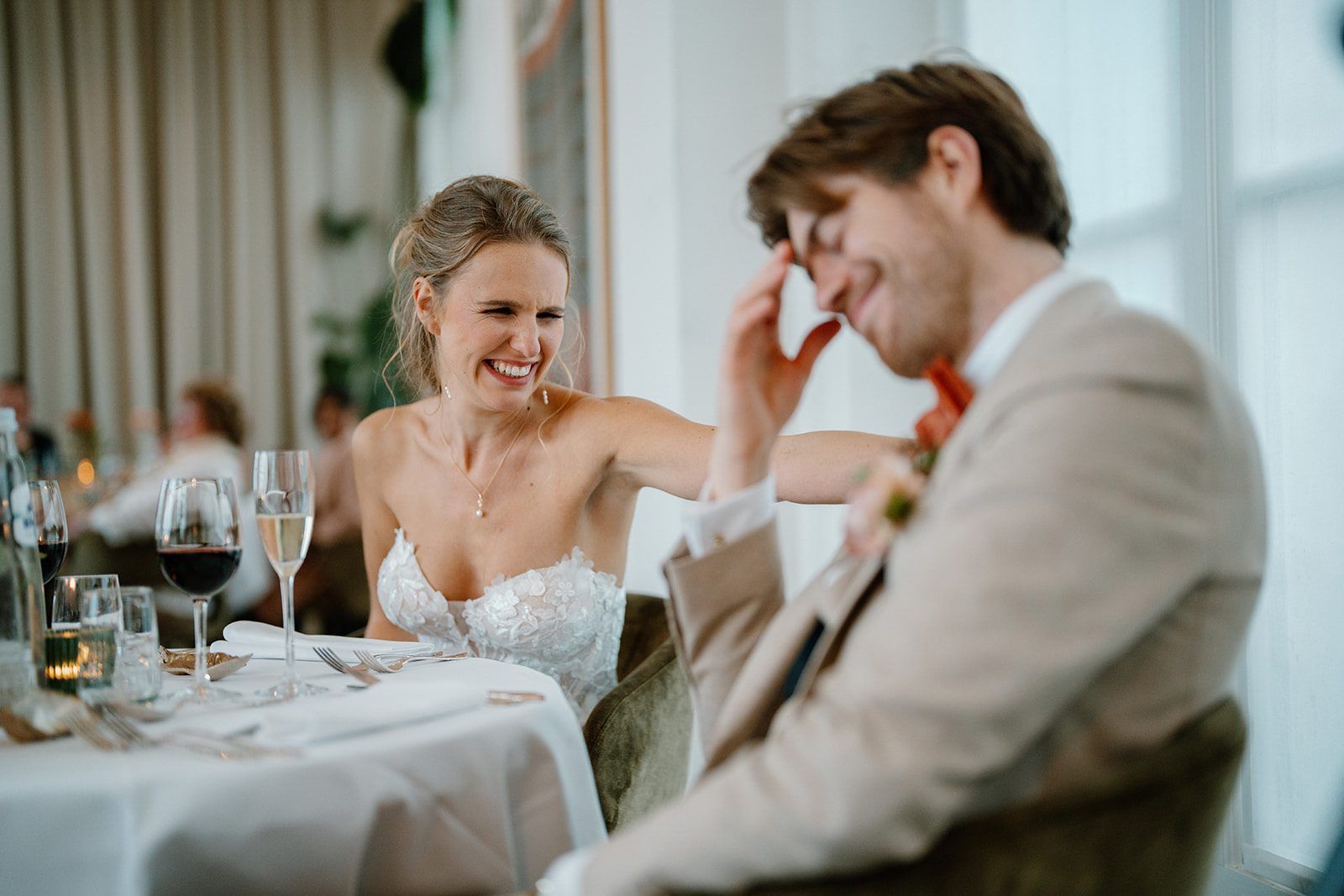 Les mariés éclatent de rire à table, verres de vin devant eux