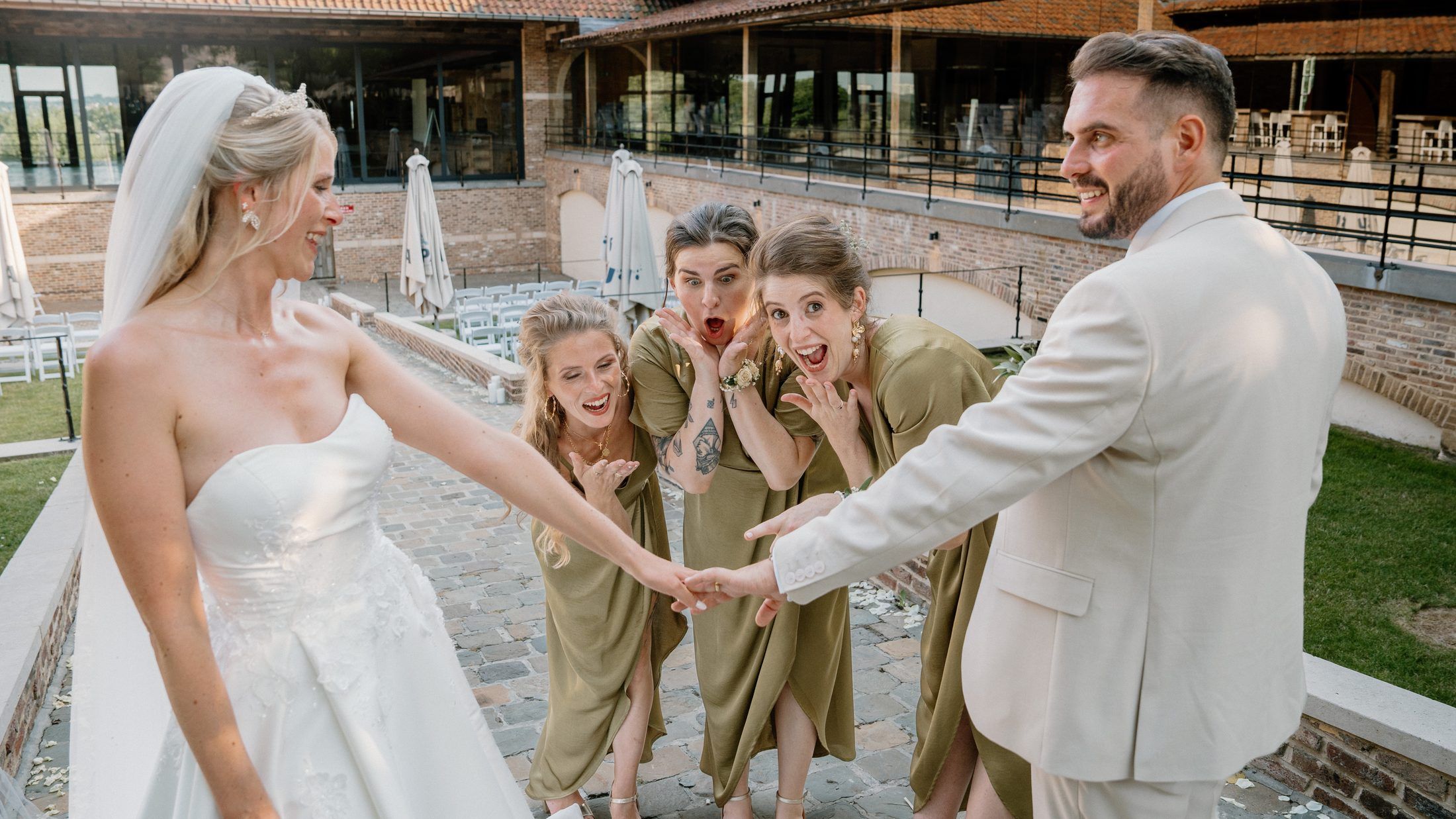 Les mariés se tiennent la main, demoiselles d'honneur exclamant leur joie autour d'eux