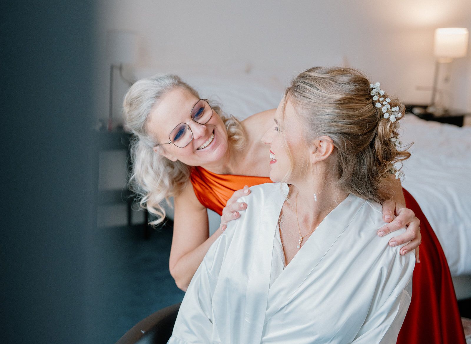 La mère de la mariée pose les mains sur ses épaules en souriant