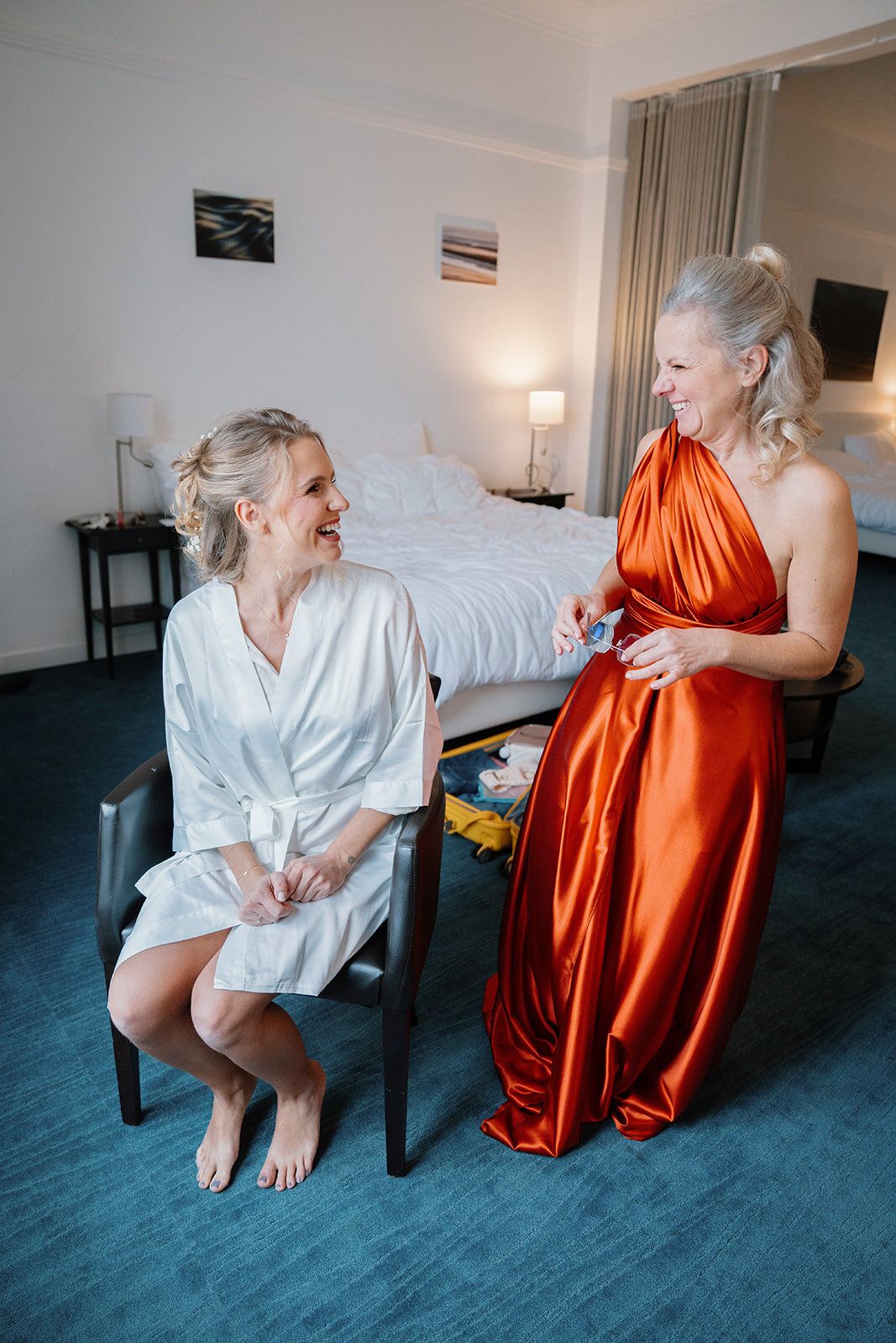 La mariée et sa mère éclatent de rire dans la chambre d'hôtel