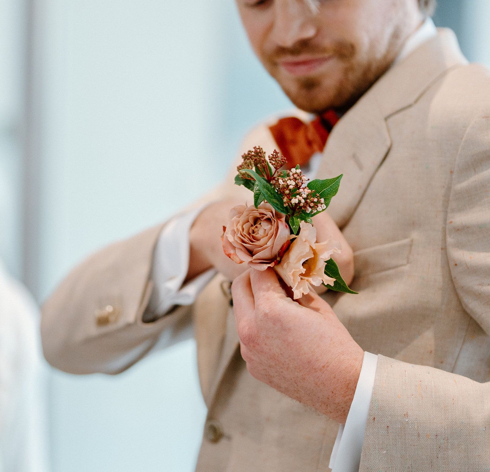 Le marié ajuste sa boutonnière de roses avant la cérémonie