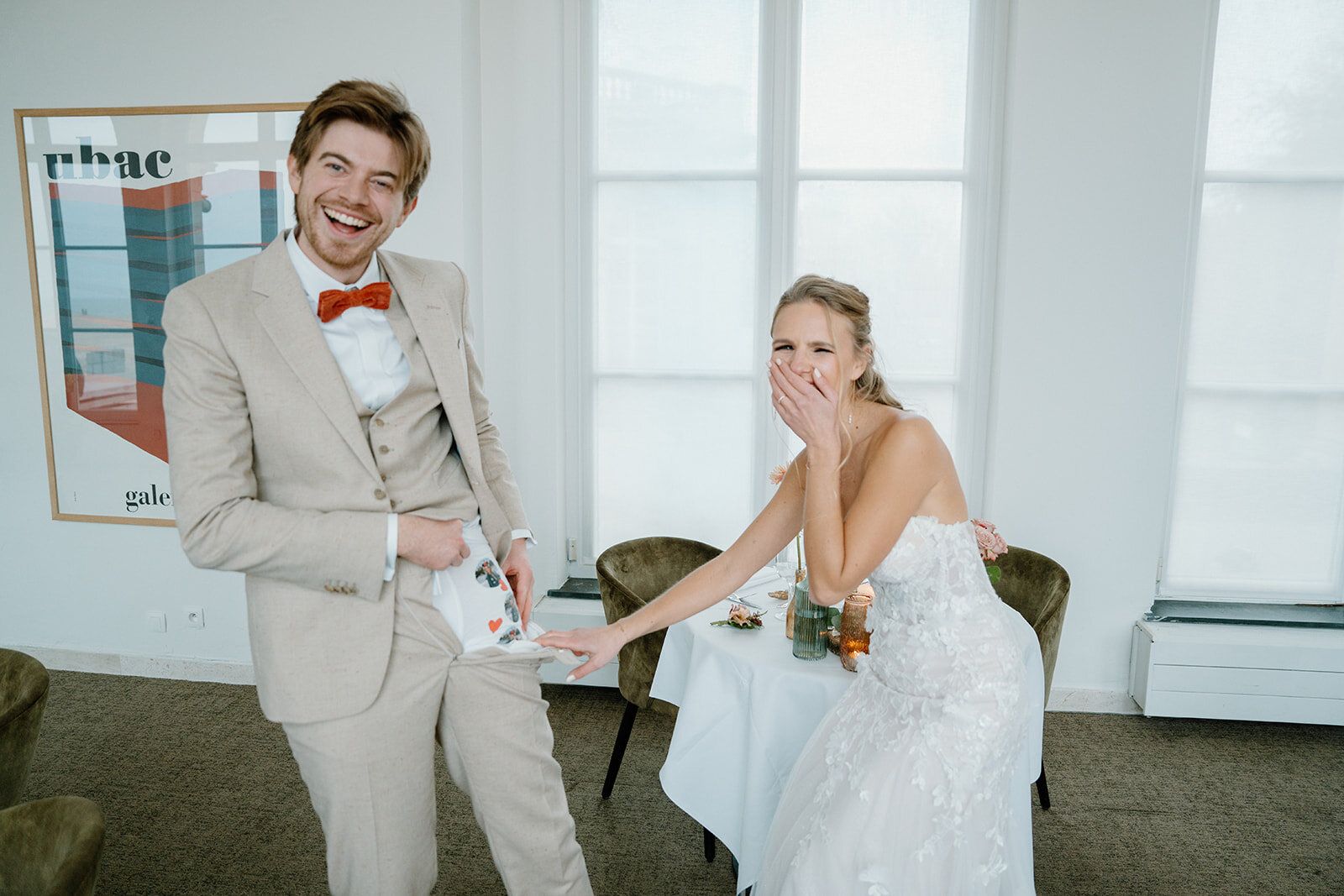 Les mariés éclatent de rire à table, la mariée couvrant sa bouche
