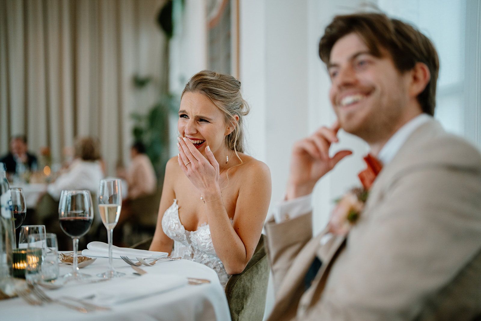 La mariée rit aux éclats à table, le marié souriant à ses côtés