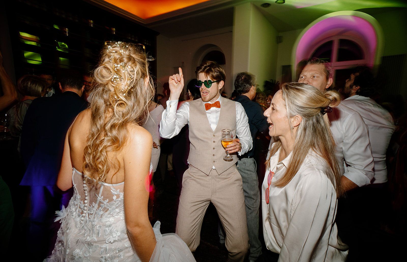 Un invité en lunettes cœur danse en pointant le doigt, verre à la main
