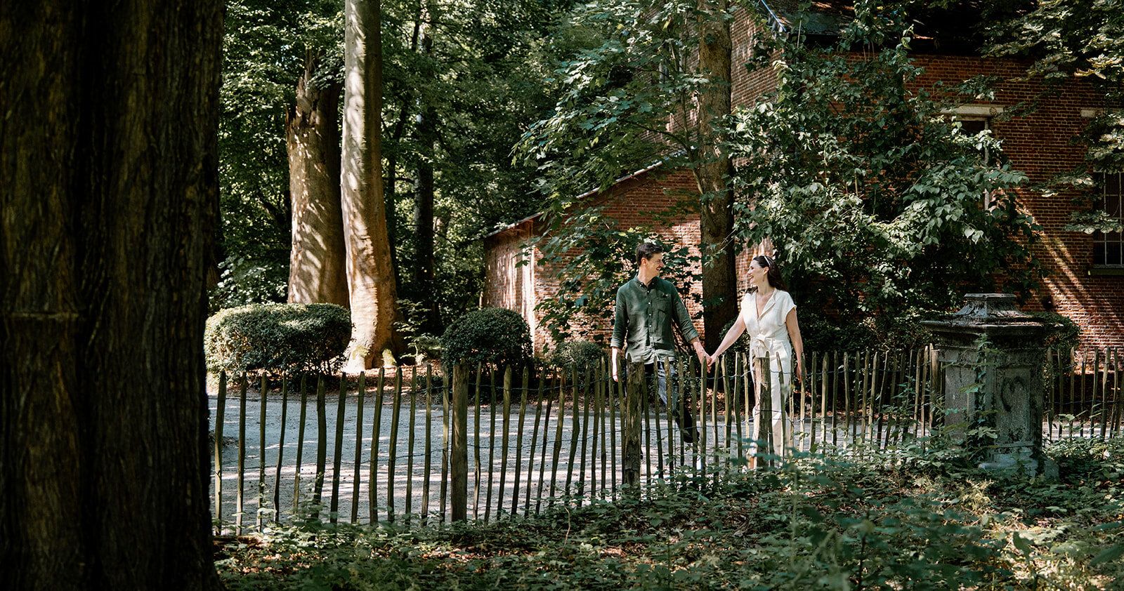 Le couple marche main dans la main le long d'une clôture en bois