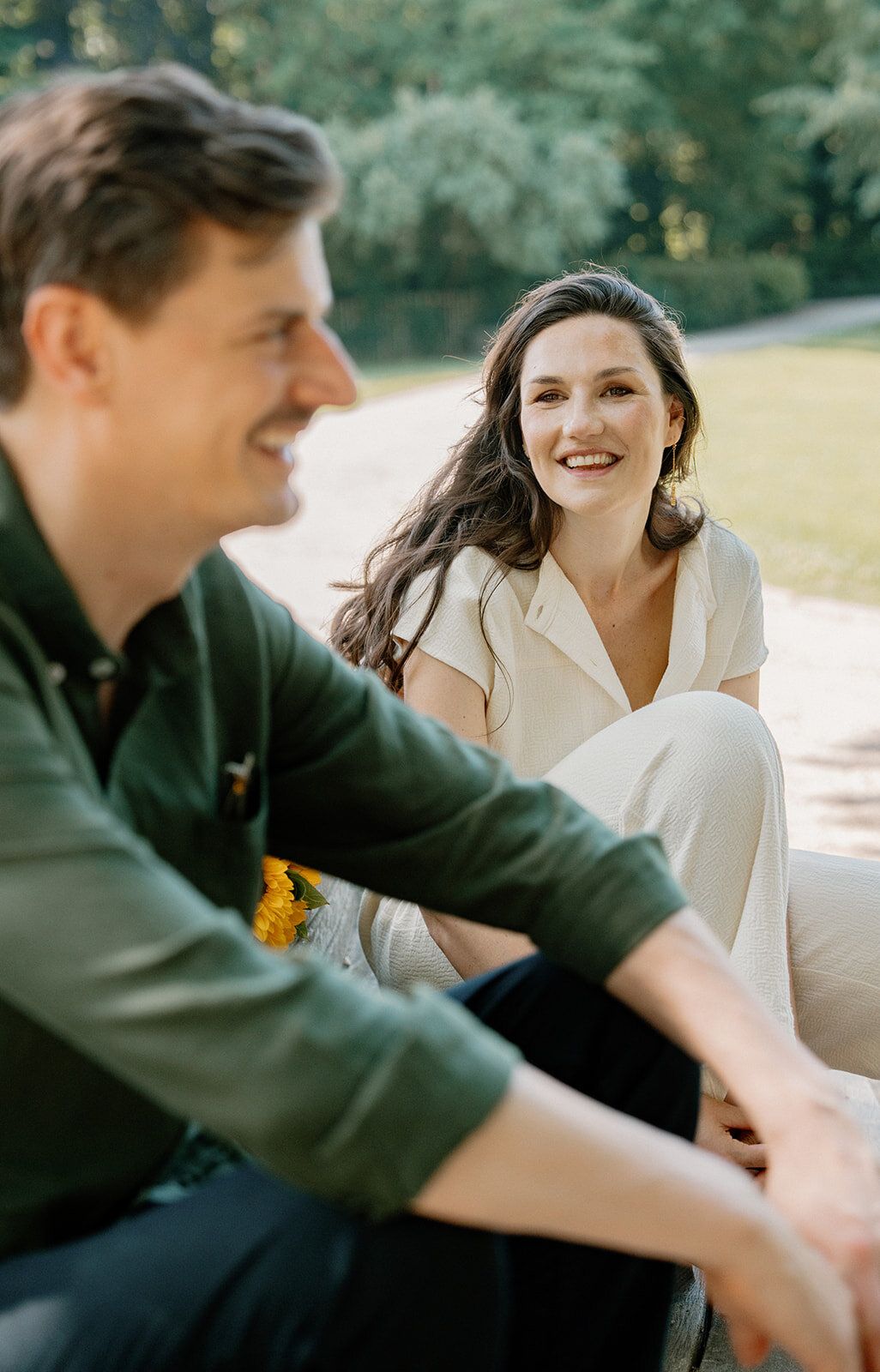 Le couple assis dans un parc, la femme souriant à l'homme en premier plan