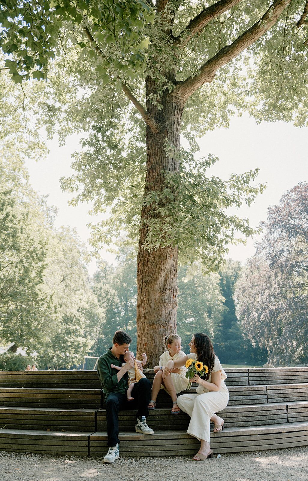 La famille assise sous un grand arbre, sur des gradins en bois